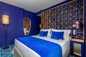 1 dormitorio azul con 1 cama grande con almohadas azules en Room Mate Macarena – Gran Vía en Madrid