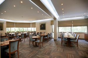 een eetkamer met tafels, stoelen en ramen bij Kaya Prestige Oteli in Izmir