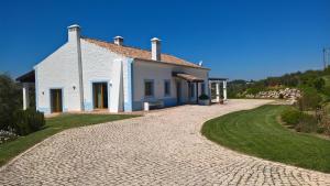 una pequeña casa blanca con entrada adoquinada en Monte da Sapaleira, en Aljezur