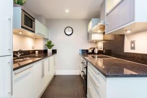 a kitchen with white cabinets and a clock on the wall at Veeve - River Views from Vauxhall in London