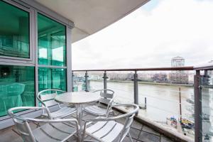 a table and chairs on a balcony with a view of a river at Veeve - River Views from Vauxhall in London