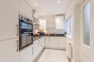 uma cozinha branca com armários brancos e uma janela em Perfectly Located 4 Storey Townhouse With 2 Parking Spaces In Central Harrogate em Harrogate