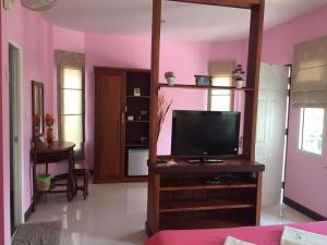 a living room with a tv and a pink wall at Montra Resort in Ko Larn