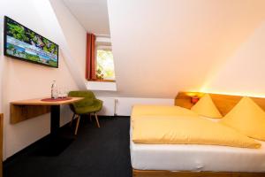 WillebadessenにあるWohlfühlhotel IM SCHLOSSPARK - Self CheckInのベッドとテーブルが備わるホテルルームです。