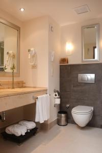 
a bathroom with a toilet a sink and a mirror at Korumar Hotel Deluxe in Kuşadası
