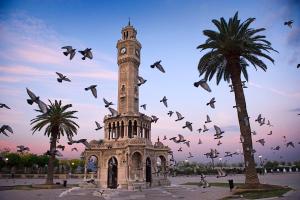een klokkentoren met een zwerm vogels die er omheen vliegen bij Kaya Prestige Oteli in Izmir
