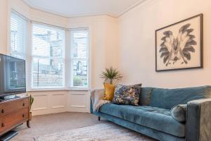 ein Wohnzimmer mit einem blauen Sofa und einem TV in der Unterkunft Perfectly Located 4 Storey Townhouse With 2 Parking Spaces In Central Harrogate in Harrogate