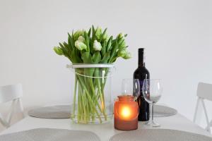 a table with a vase of flowers and a bottle of wine at Elite Apartments Nadmorski Brzeźno in Gdańsk