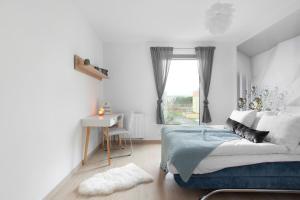 a bedroom with a bed and a desk and a window at Elite Apartments Nadmorski Brzeźno in Gdańsk