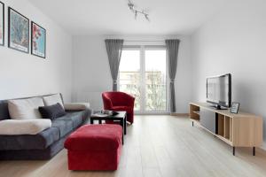 格但斯克的住宿－Elite Apartments Nadmorski Brzeźno，带沙发和红色椅子的客厅