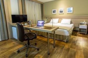 um quarto de hotel com uma cama e uma secretária com um computador portátil em Intercity Manaus em Manaus