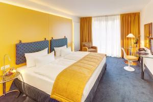 ein Hotelzimmer mit einem großen Bett mit gelber Wand in der Unterkunft Alexander am Zoo in Frankfurt am Main