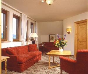 a living room with a couch and a table with flowers at Landhotel Reckenberg in Stegen