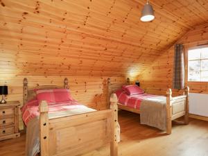 a bedroom with two beds in a log cabin at Allt Lodge in Inverness