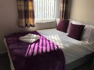 a bed with a purple blanket on it with a window at Hygge House in Middlesbrough