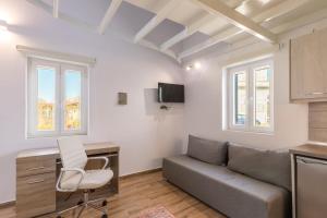 een woonkamer met een bank, een bureau en ramen bij K and B corfustudios in Corfu-stad