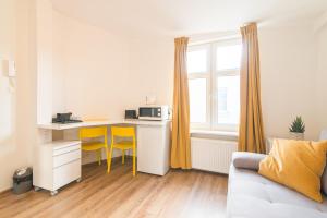 a room with a desk with a microwave and yellow chairs at Studio Błękitny Wieloryb przy plaży, molo, idealny dla podróżników in Sopot
