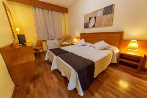 Cette chambre comprend un grand lit et une télévision. dans l'établissement Hotel de Montaña Rubielos, à Rubielos de Mora