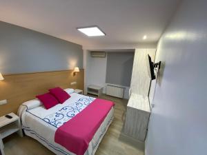 - une chambre avec un grand lit et une couverture rose dans l'établissement Hotel San Juan, à Miguelturra