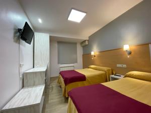 um quarto de hotel com duas camas e uma televisão de ecrã plano em Hotel San Juan em Miguelturra