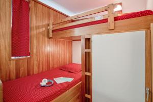 a small room with a bunk bed with red sheets at Pierre et Vacances Serre Chevalier Chantemerle in Saint-Chaffrey