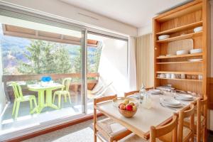 a dining room with a table and a large window at Pierre et Vacances Serre Chevalier Chantemerle in Saint-Chaffrey