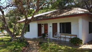 a small white house with a tree in front of it at A Rocha Eco-Lodge & Conservation Centre in Watamu