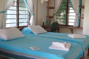 a bedroom with a blue bed with towels on it at A Rocha Eco-Lodge & Conservation Centre in Watamu