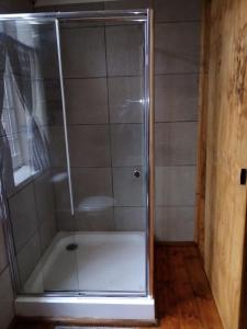 a shower with a glass door in a bathroom at Reis n Rus in Harrismith