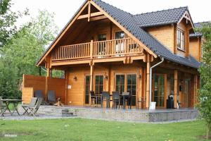 a large wooden house with a deck and patio at Houten villa Albert in Den Ham