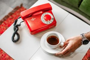 una persona sosteniendo una taza de café y un teléfono rojo en LOFT Hostel, en Gyumri