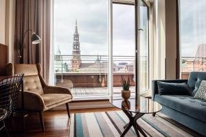 a living room with a blue couch and a large window at AMERON Hamburg Hotel Speicherstadt in Hamburg