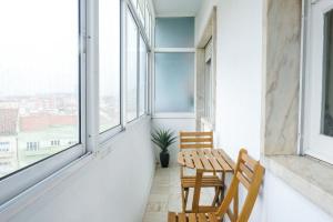 リスボンにあるBarao Apartment by Trip2Portugalのバルコニー(椅子2脚、テーブル、窓付)