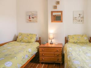 a bedroom with two beds and a night stand with a lamp at Chapel Cottage in Filey