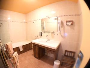 La salle de bains est pourvue d'un lavabo, d'une baignoire et d'un miroir. dans l'établissement Auv'hôtel, à Mauriac
