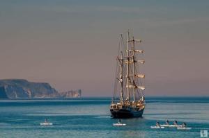 ein großes Boot im Wasser mit Menschen in Booten in der Unterkunft Strandview Ground Floor Beach Apartment in Ballycastle