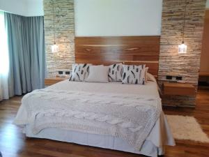 a bedroom with a large white bed with a brick wall at Noha Casa de Campo in Colón