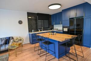 uma cozinha com armários azuis e uma mesa de madeira em Royal Serenity Penthouse em Tiberias