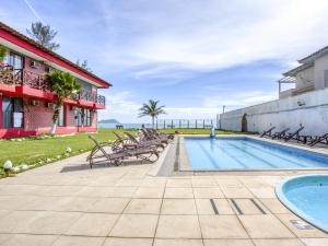 a swimming pool with chairs next to a building at Rasa Hotel in Búzios