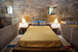 a bedroom with a bed in a stone wall at Quinta de Santa Baia in Gaifar