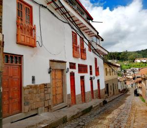 Une allée dans une vieille ville avec des portes rouges dans l'établissement ValPer boutique, à Cusco