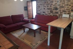 sala de estar con sofá rojo y mesa en La Carcaña, en Rebollar