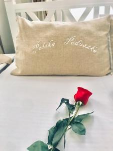 a pillow and a red rose on a bed at Polska Poduszka in Lviv