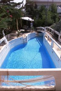 a swimming pool with blue water and a bridge at Myrmidon Hotel in Agia Marina Aegina