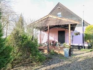 Casa rosa con porche con mesa en The Haybarn, en West Bradenham