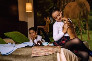 a woman sitting on a bed holding a stuffed animal at Hotel Albaida Nature in Mazagón
