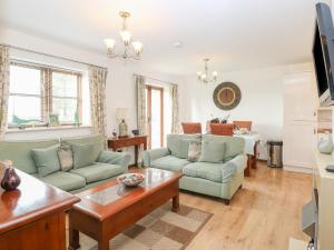 uma sala de estar com sofás verdes e uma mesa em The Haybarn em West Bradenham