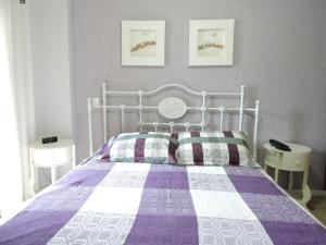 - une chambre avec un lit doté d'une couette violette et blanche dans l'établissement 1 Flats Capitania Varan, Wifi, Pitangueiras vista ao mar, à Guarujá