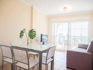 a dining room with a table and chairs and a couch at Residencial Los Almendros Playa Romana in Alcossebre