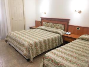 a hotel room with two beds and a phone on a table at Hotel Malaga in Avellino